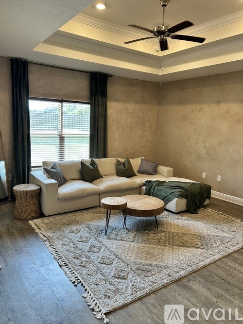 A living room with a white couch and a rug on the floor.