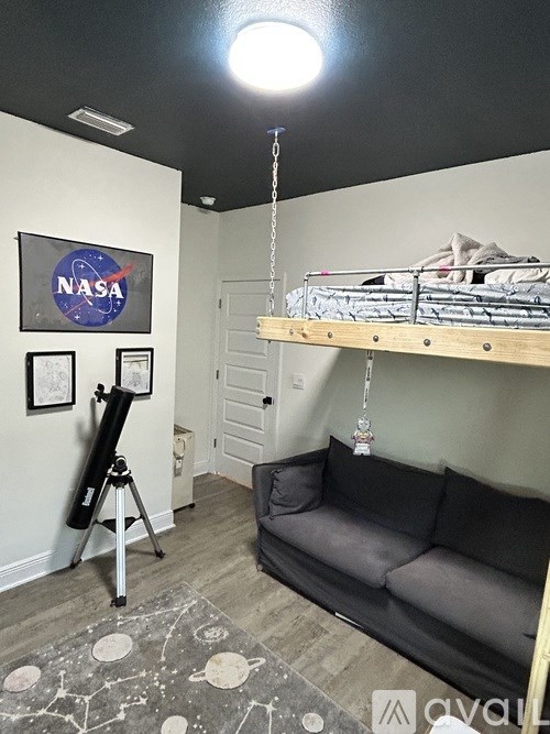 A room with a NASA poster on the wall and a telescope on a tripod.