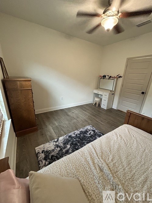 A bedroom with a bed, a dresser, and a ceiling fan.
