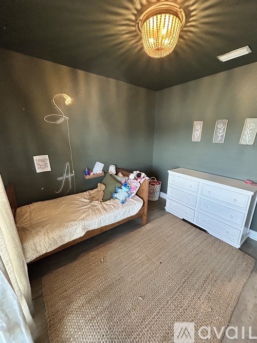 A bedroom with a bed, dresser, and a chandelier.