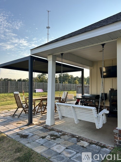 A covered patio area with a white bench and a table.