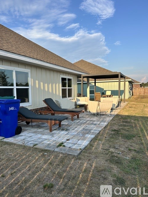 A patio with a blue trash bin and a black chair.