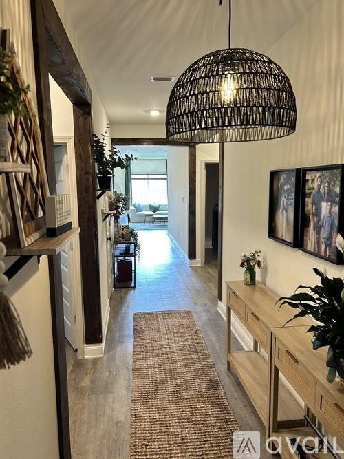 A long hallway with a rug on the floor and a hanging light fixture.