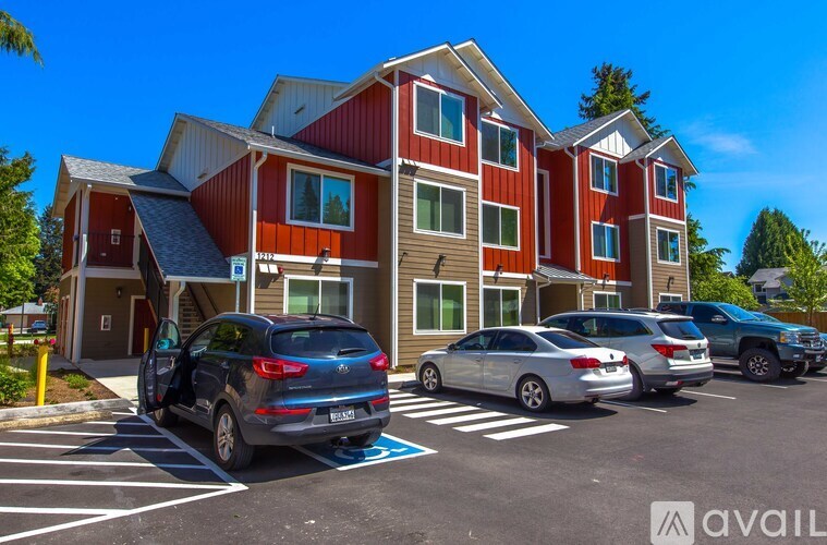 A parking lot with cars and a multi-story building with a red and white exterior.