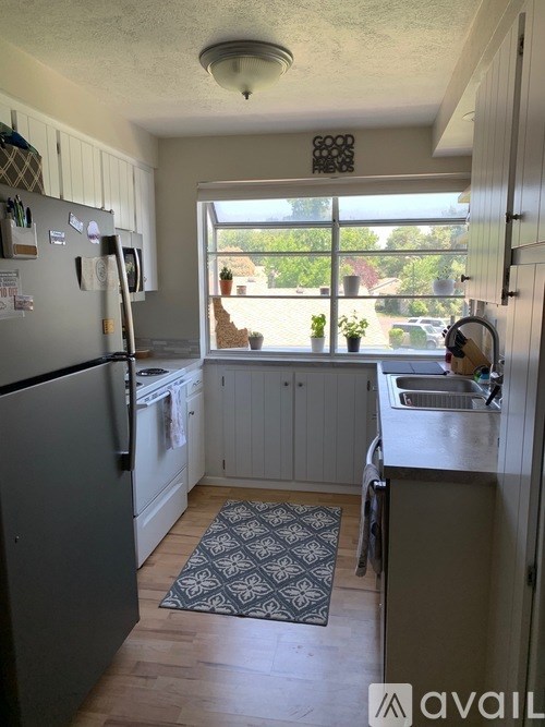 A kitchen with a refrigerator, sink, and window.