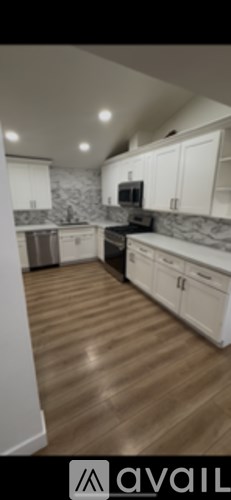 A kitchen with white cabinets and a wooden floor.