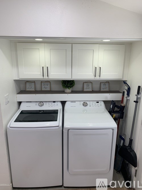 A bathroom with a white tub, a wooden cabinet with a mirror above it, and a glass shower door.