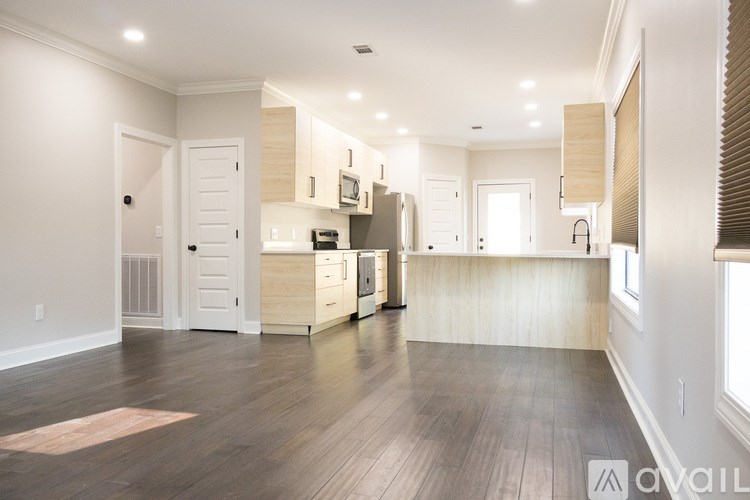 A spacious kitchen with wooden floors and white walls.