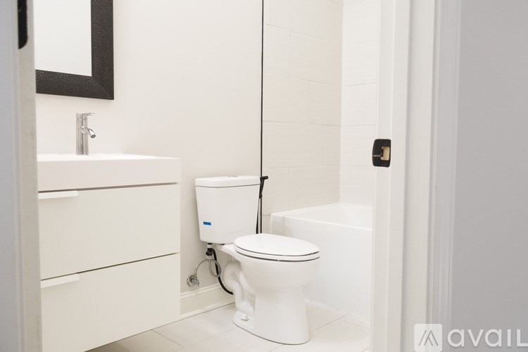 A white toilet is in a bathroom with a sink and mirror.