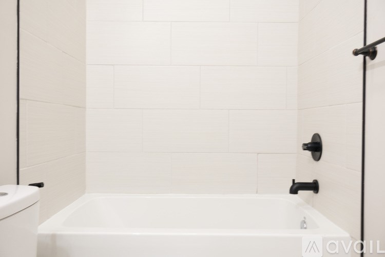 A white bathroom with a toilet, tub, and towel rack.