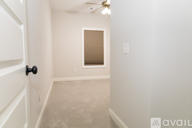 A room with a door, a window with blinds, and a ceiling fan.