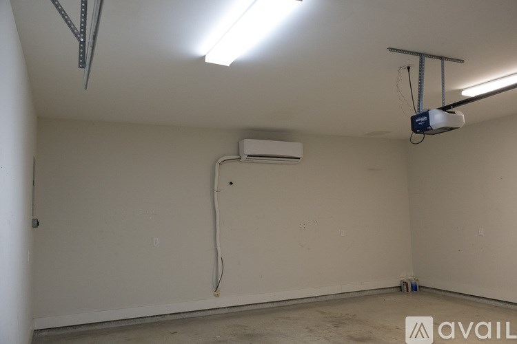 A room with a white wall and a white ceiling with a light fixture and a white air conditioner unit.