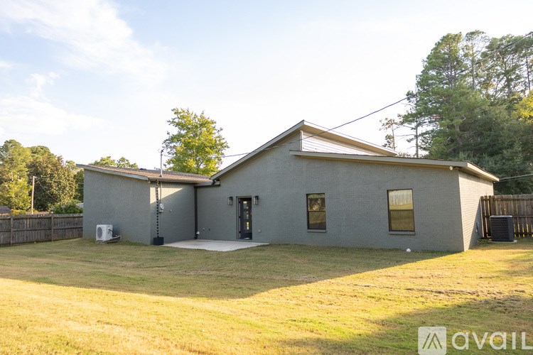A house with a grey exterior and a brown roof is surrounded by a grassy yard.