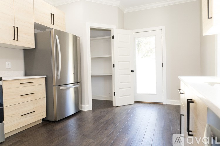 A kitchen with a refrigerator, sink, and cabinets.