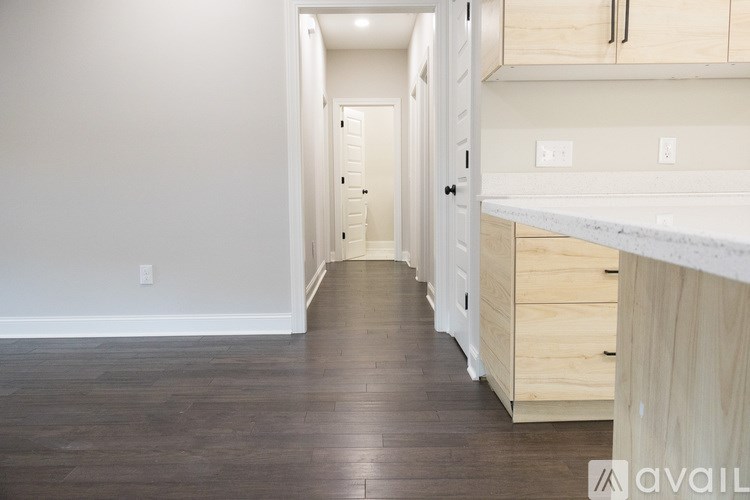 A long hallway with a white counter on the right and wooden floors.