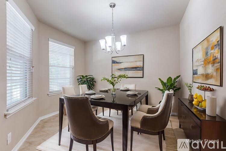 A dining room with a table set for four and a chandelier hanging from the ceiling.