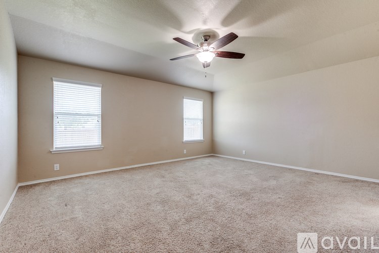 A room with a ceiling fan and two windows.