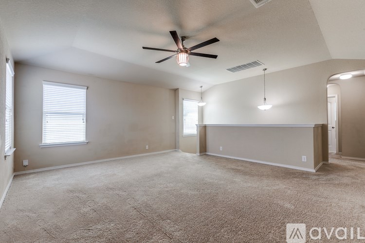 A spacious room with a ceiling fan and carpeted floor.