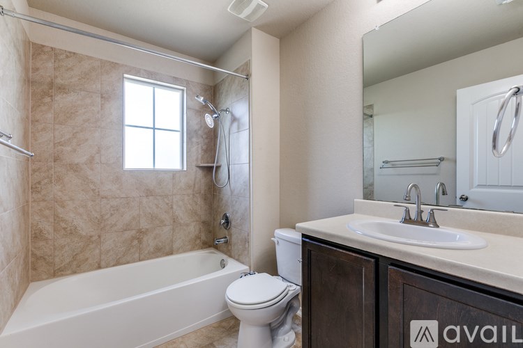 A bathroom with a tub, toilet, sink and mirror.