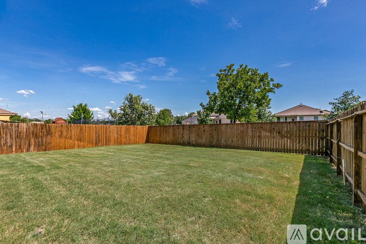 A backyard with a wooden fence and green grass.