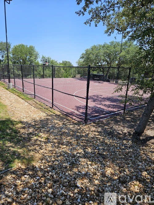 Tennis court surrounded by a black fence.
