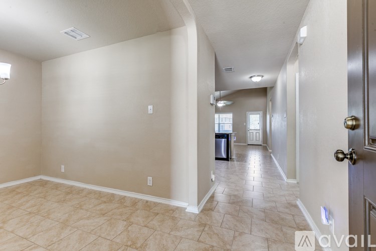A hallway with tiled flooring and a door on the right.