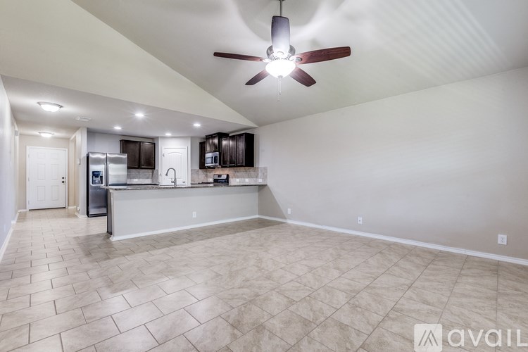 A spacious kitchen with a fan and tile flooring.