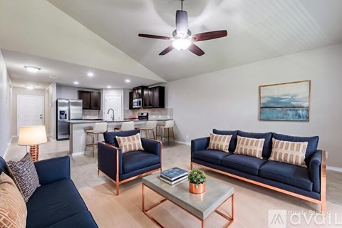 A living room with a blue couch and a ceiling fan.