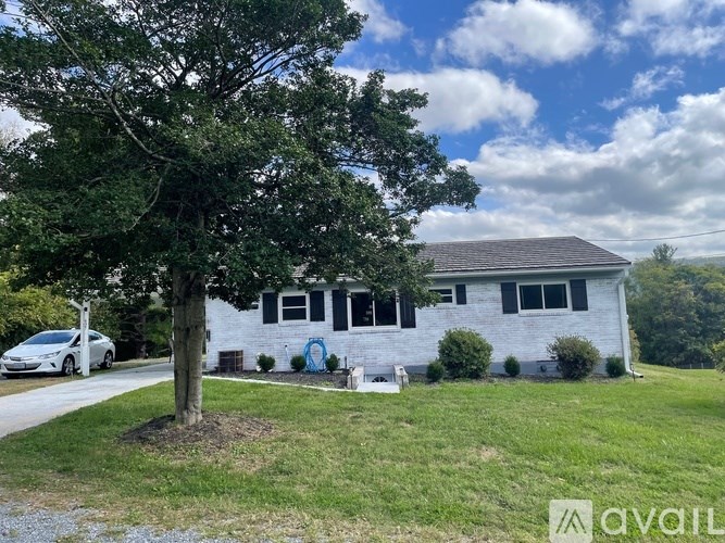 A rural landscape with a gravel path, a wooden fence, and a house in the distance.