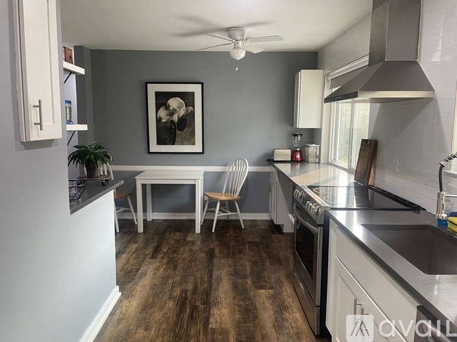 A kitchen with a wooden floor and a ceiling fan.