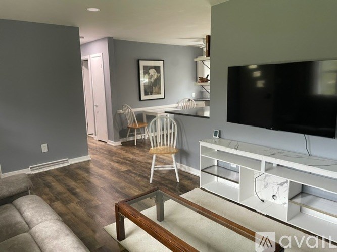 A living room with a grey couch, a wooden coffee table, and a white entertainment center.