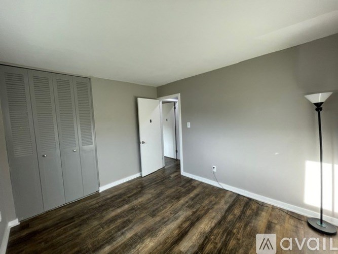A room with wooden flooring and a lamp on the right side.