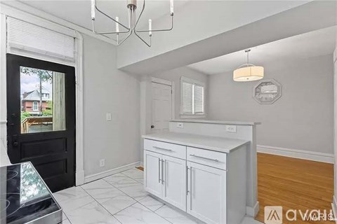 A kitchen with white cabinets and a black door.