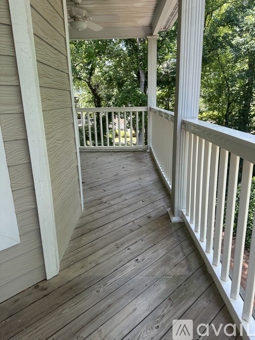 A wooden deck with a white railing and a ceiling fan.