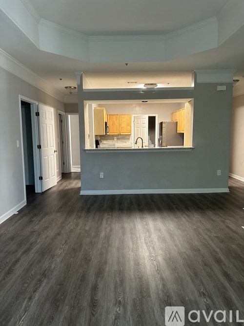 A spacious room with wooden flooring and a kitchen area in the background.