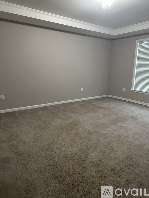 A room with a carpeted floor and a window with blinds.