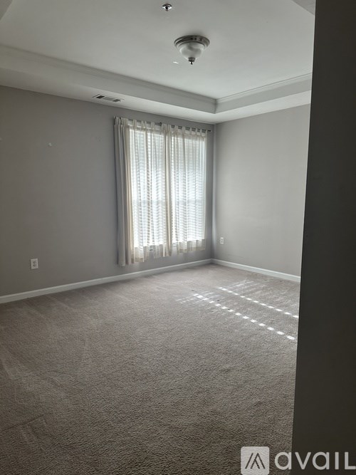 A room with a carpeted floor and a window with curtains.