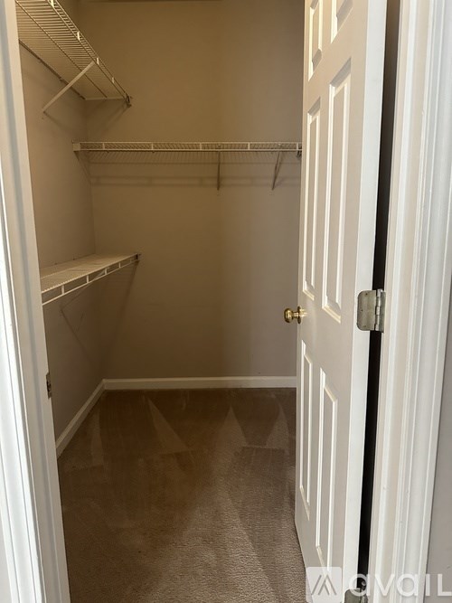 A white door is open to a small, empty room with a carpeted floor.