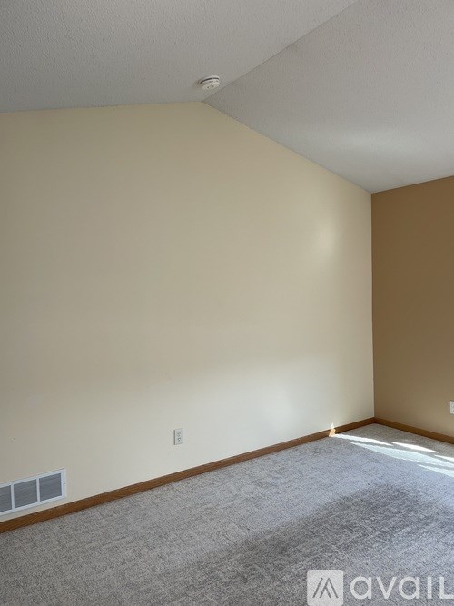 A room with a carpeted floor and a window letting in sunlight.