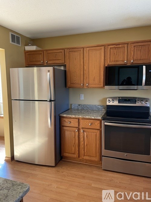 A kitchen with a stainless steel refrigerator, microwave, oven, and cabinets.