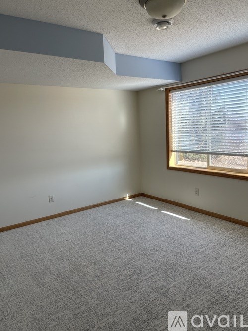 A room with a carpeted floor and a window with blinds.