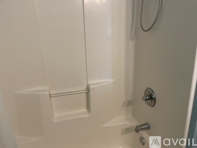 A white bathroom with a shower door and a silver handle.