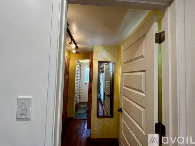 A hallway with a white door and a light switch on the wall.