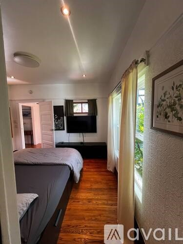 A bedroom with a bed, a TV, and a window with curtains.