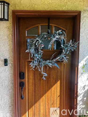 A wooden door with a wreath and a black handle.