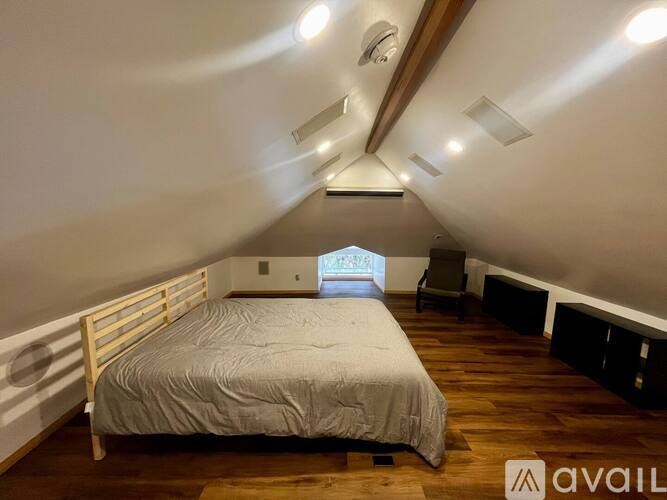 A bedroom with a bed, wooden floors, and a window.