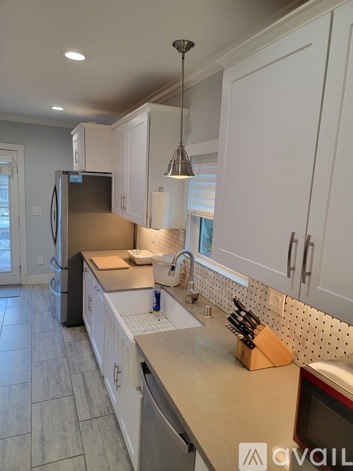 A kitchen with white cabinets and a black refrigerator.