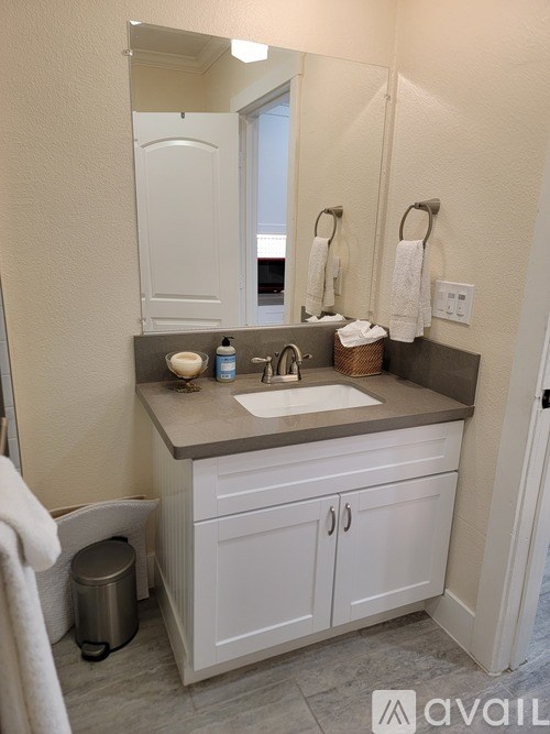 A bathroom with a white cabinet and a mirror above the sink.