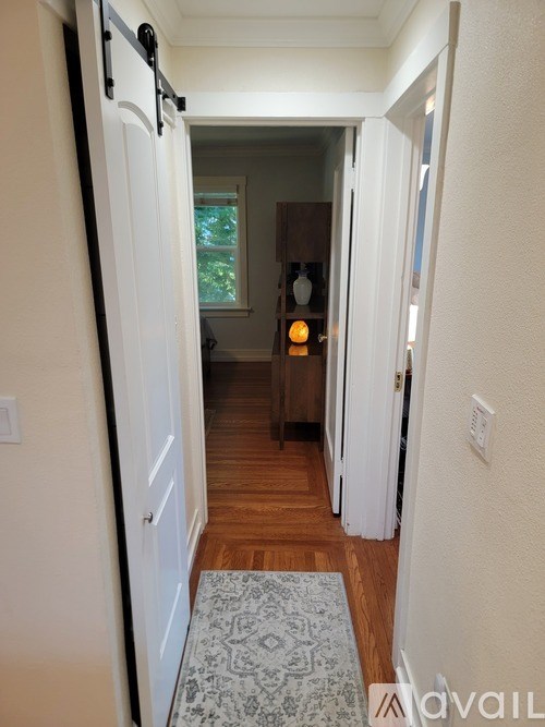 A hallway with a rug on the floor and a door on the left.