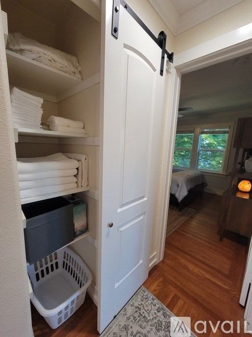 A white closet with towels and a basket in it.